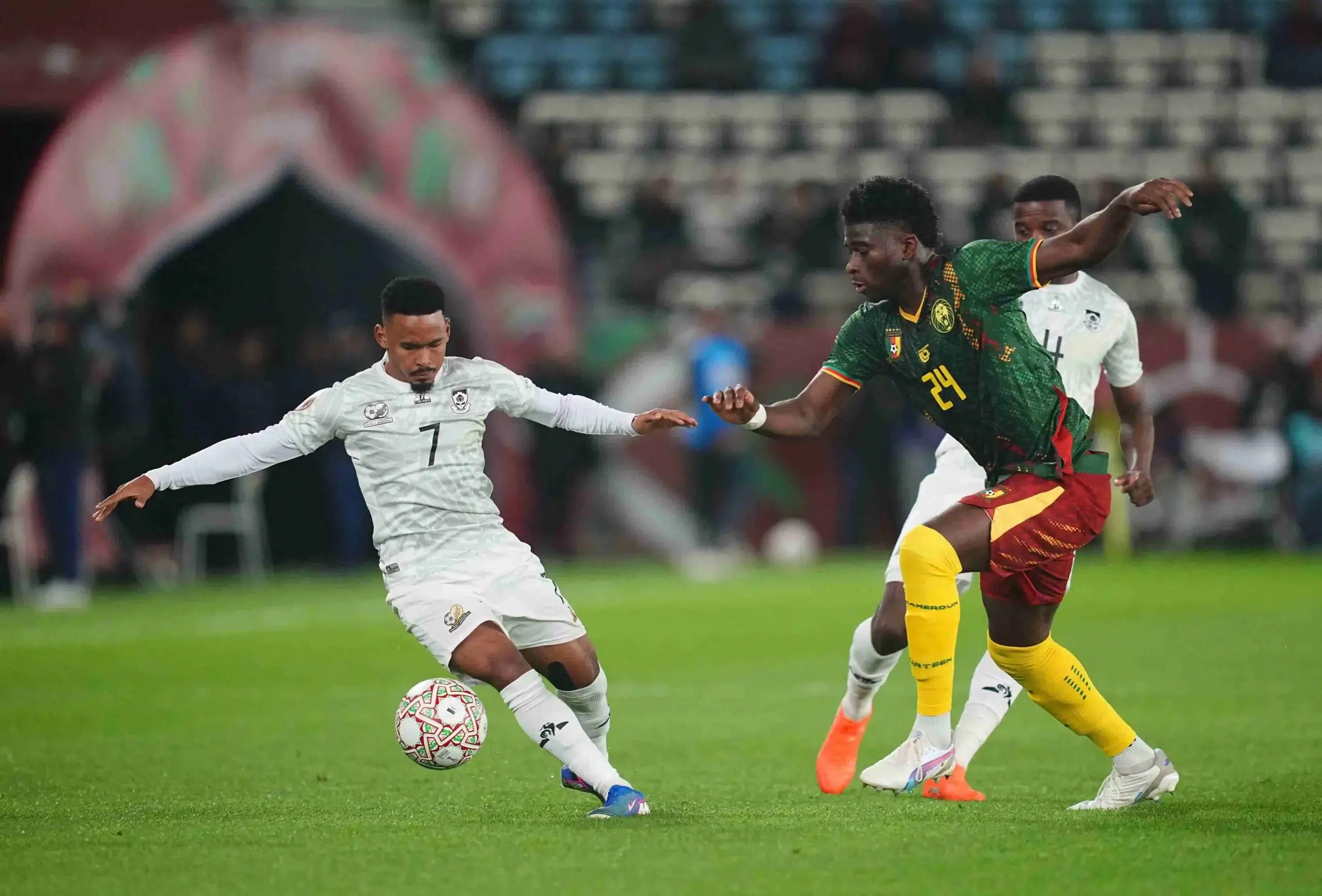 Oswin Reagan Appollis of South Africa and Baleba Carlos Noom Quomah of Cameroon battle for the ball during a 2025 AFCON Africa Cup of Nations game, South Africa vs Cameroon, at Al Medina stadium, Rabat, Marocco.
